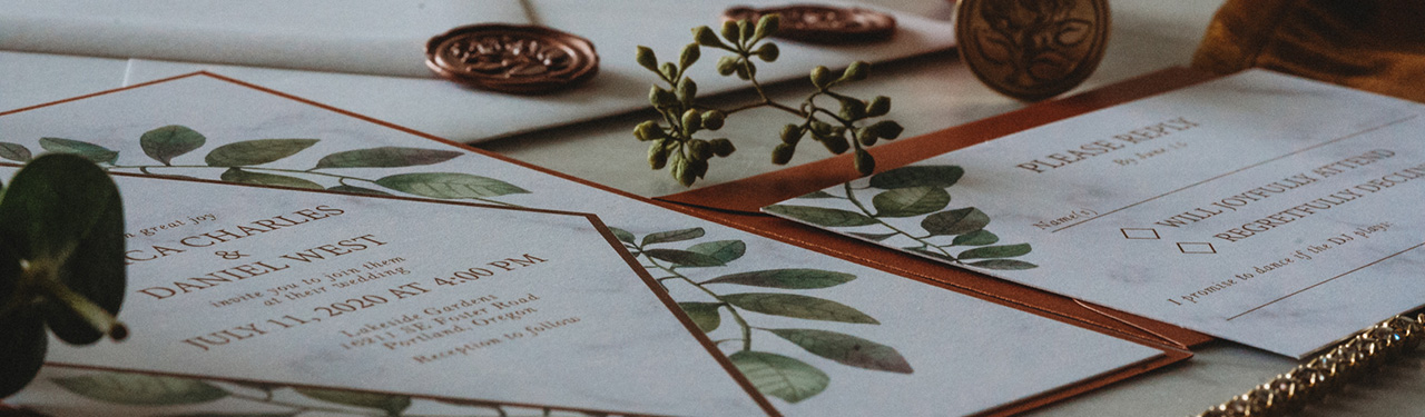 Wedding invitation close up with wax seals and greenery